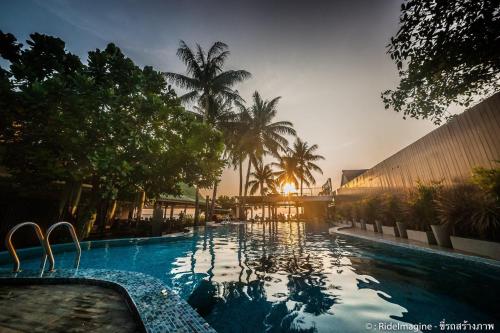 a large swimming pool with palm trees and a building at Wind Beach Resort in Koh Tao