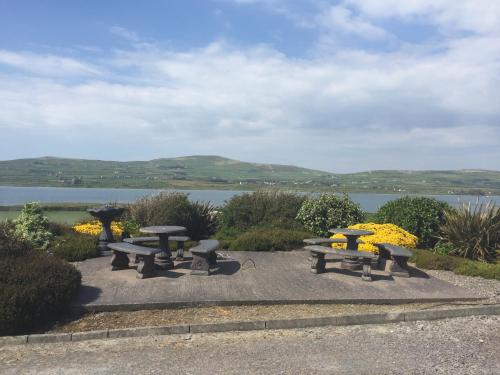 a group of picnic tables with a view of a lake at Skellig Port Accommodation - 1 Studio Bed Apartment in Portmagee