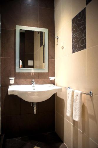 a bathroom with a sink and a mirror and towels at Hotel Victoria in Panagyurishte