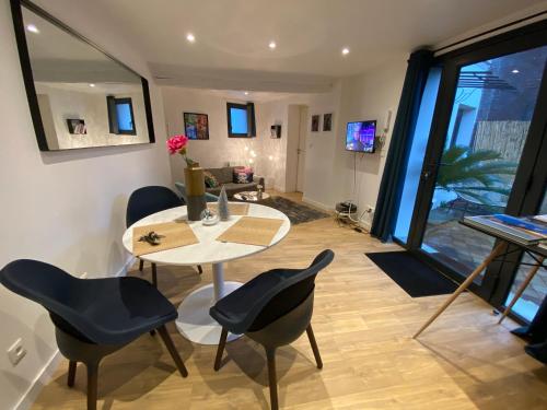 un comedor con mesa y sillas y una habitación con ventana en Joli appartement avec cour privée proche gare & centre ville, en Rouen