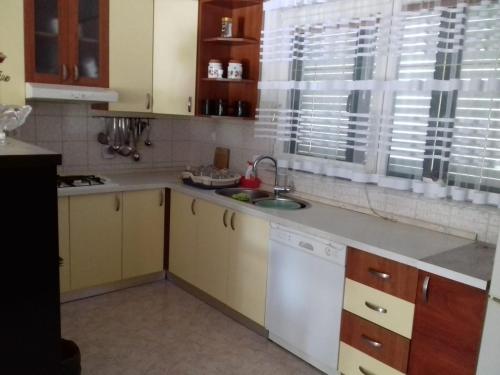 eine Küche mit gelben Schränken, einem Waschbecken und einem Fenster in der Unterkunft Apartmani Bilić in Dugi Rat