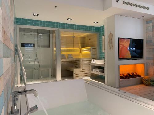 een badkamer met een bad, een tv en een open haard bij Van der Valk Hotel Houten Utrecht in Houten