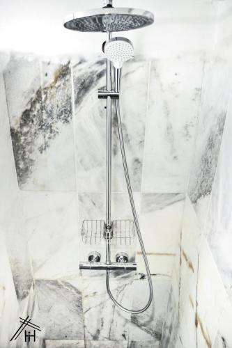 a shower head in a bathroom with marble walls at AiM HOUSE in Marrakech