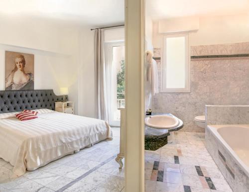 a bedroom with a bed and a tub and a sink at Hotel Shelley e delle Palme in Lerici