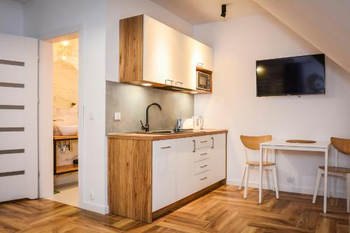 a kitchen with a sink and a counter with a table at Miło Cię widzieć in Łeba