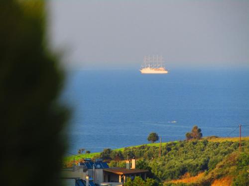 a large container ship in the ocean next to a house at Aristos Apartments & Suites in Stalos