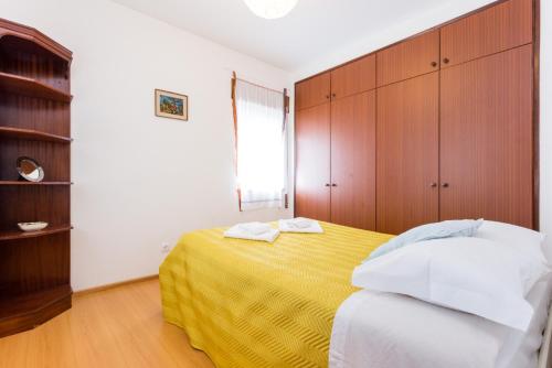 1 dormitorio con cama amarilla y armarios de madera en Cegonha do mar, en Aljezur