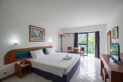 a bedroom with a bed and a desk and a television at Samba Angra dos Reis in Angra dos Reis