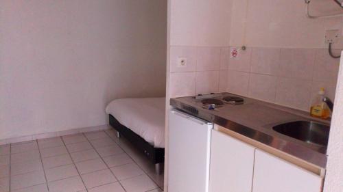 une petite cuisine avec un évier et un lit dans l'établissement Résidence le Pastel François Verdier, à Toulouse