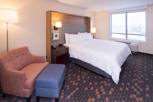 a hotel room with a bed and a chair at Holiday Inn - Kalamazoo West by IHG in Kalamazoo
