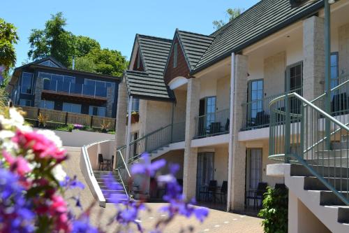 un edificio con escaleras y flores púrpuras en el primer plano en Colonial Lodge Motel, en Taupo