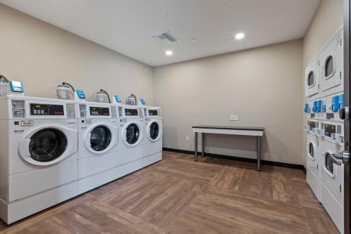 a laundry room with three washing machines and a table at Extended Stay America Premier Suites - Tampa - Gibsonton - Riverview in Gibsonton