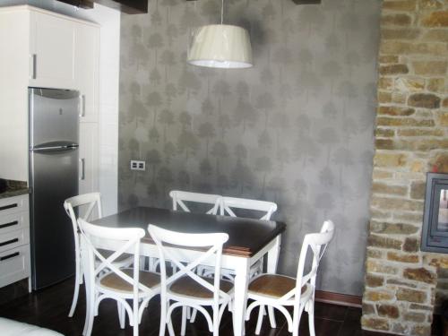 eine Küche mit einem Tisch mit Stühlen und einem Kühlschrank in der Unterkunft Casa Rural Manuel de Pepa Xuaca in Tuilla