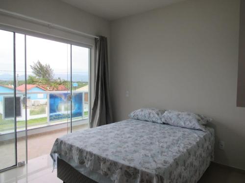 a bedroom with a bed and a large window at Residencial Coração do Mar in Palhoça