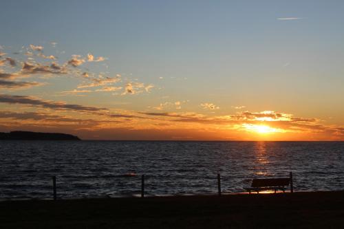 a sunset over the ocean with a bench on the beach at Landhaus Alt Reddevitz in Middelhagen