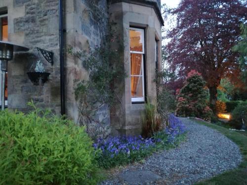 a stone house with blue flowers in front of it at Lubnaig Guest House in Callander