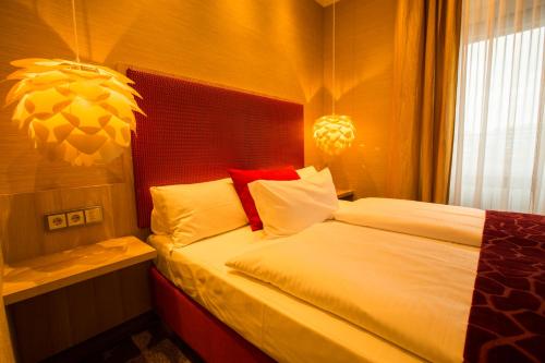 a bedroom with a bed with red and white pillows at Top Hotel Hammer - Mainz Hauptbahnhof in Mainz