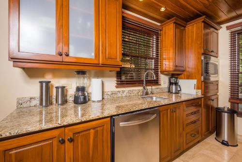 una cucina con armadi in legno e lavandino di Jet Luxury at Langosta Beach Resort & Villas a Tamarindo