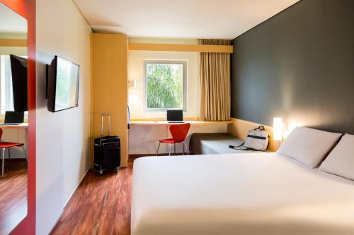 Habitación de hotel con cama, escritorio y ventana en Ibis Monterrey Valle en Monterrey