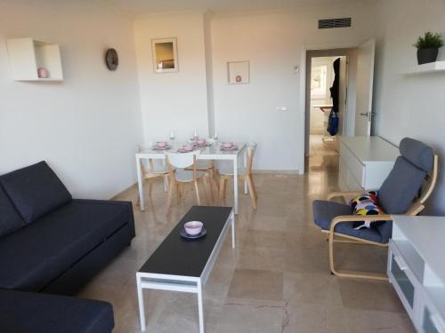 salon z kanapą i stołem w obiekcie CASARES appart 2 ch dans parc tropical avec vue sur mer, montagne et piscine w mieście Casares