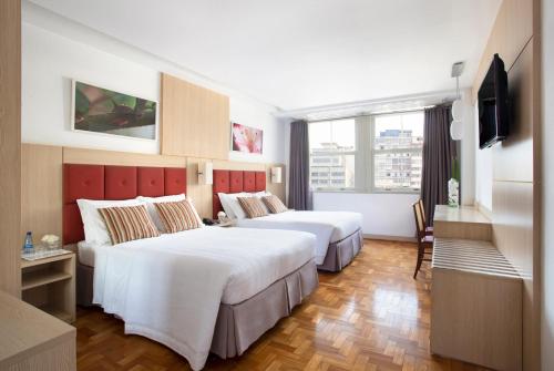 um quarto de hotel com duas camas e uma televisão em Normandy Hotel em Belo Horizonte
