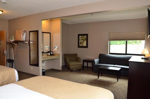 a hotel room with a bed and a couch and a chair at Qube Hotel - Polk City in Polk City