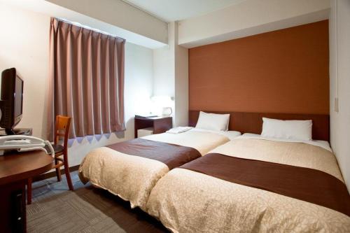 a bedroom with two beds and a desk and a television at Hamamatsu Station Hotel - Vacation STAY 65834 in Hamamatsu