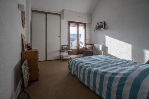 a bedroom with a bed with a blue and white blanket at Appartement Talloires vue lac et montagnes in La Pirraz