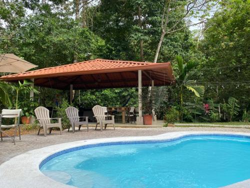 a swimming pool with chairs and an umbrella and a table at Ukinca in Uvita