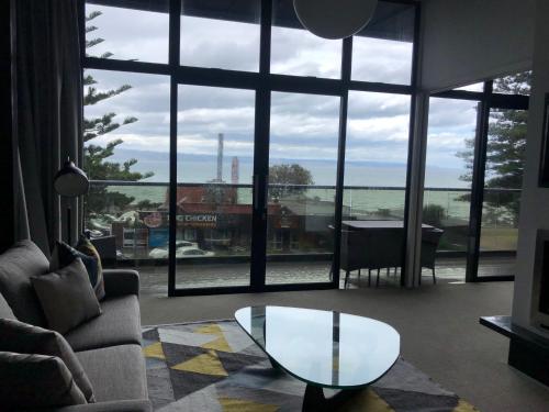 a living room with a table and a large window at Vue Apartments in Napier