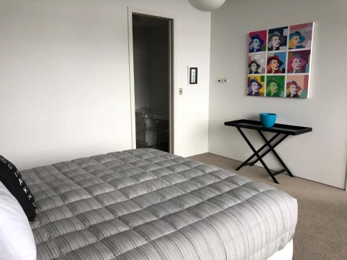 a bedroom with a bed and a table with a picture on the wall at Vue Apartments in Napier