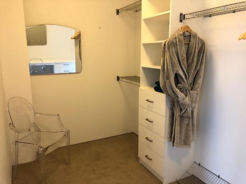 a bedroom with a dresser and a mirror and a chair at Vue Apartments in Napier
