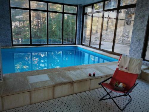 a swimming pool in a room with a chair and a red chair at "Ecológico con Piscina Climatizada" y Sauna!! in Riaza