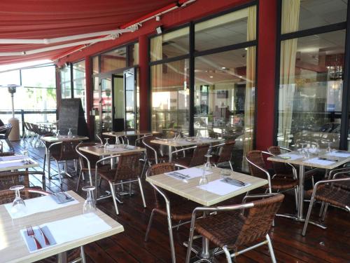 a restaurant with tables and chairs and windows at Logis Hôtel du Haut-Bugey in Oyonnax