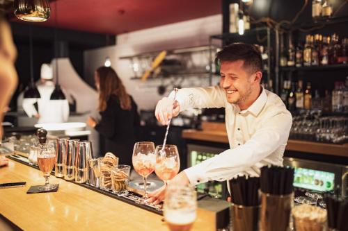 a man preparing a drink at a bar at Kurhaus Lenzerheide in Lenzerheide