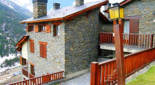 a stone house with a balcony and a wooden fence at Appartement Ona Dorada el Tarter in Ransol