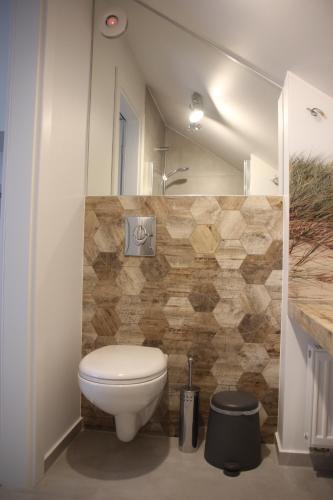 a bathroom with a white toilet and a mirror at Morska Kryjówka in Niechorze
