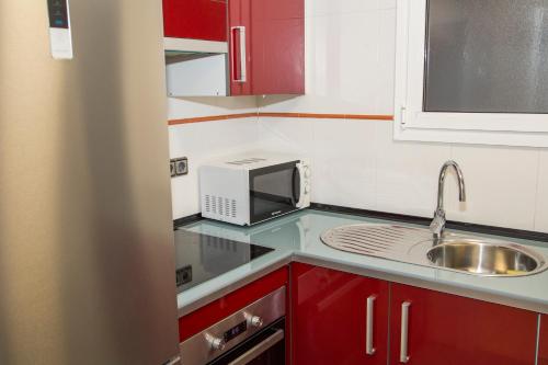een kleine keuken met een wastafel en een magnetron bij Apartamento Reus 2 - Parking gratuito in Reus