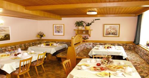 un restaurante con dos mesas con manteles blancos en Pension Carina, en Sankt Kanzian