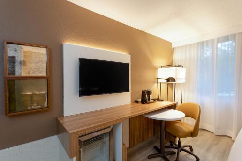 a hotel room with a desk with a television and a chair at Wyndham Garden Tallahassee Capitol Near FSU in Tallahassee