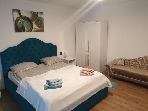 a bedroom with a blue bed with towels on it at Garsoniera Mihaela in Onești