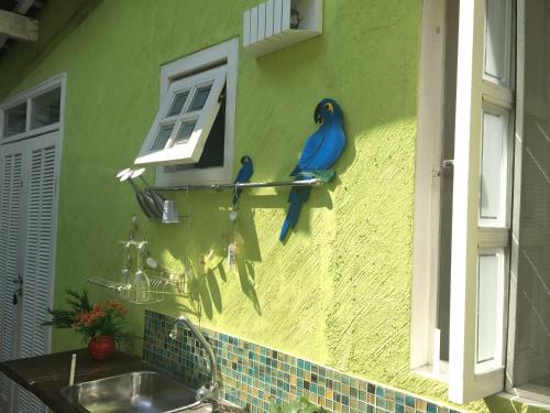 two blue birds sitting on a wall next to a sink at SUÍTES Caminho do Mar in Abraão