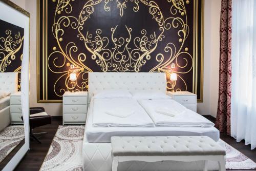 a bedroom with a white bed and a black and gold wall at Villa Apartman in Makó