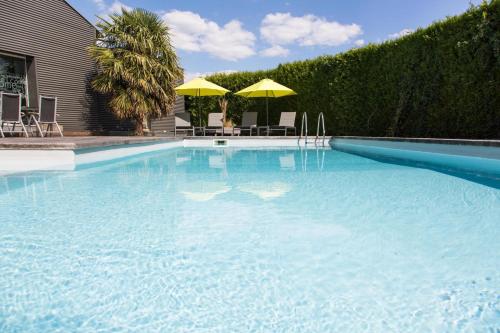 a large swimming pool with chairs and umbrellas at Gîtes de La Vesée in La Chapelle dʼArmentières