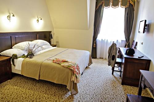 a bedroom with a bed and a desk and a window at Hotel Chutor Kozacki in Łukowe