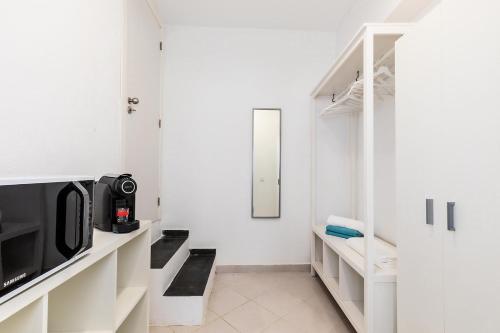 a white room with a tv and a microwave at Faro Downtown Ria Formosa Studios in Faro