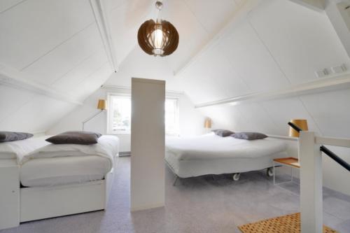 a white bedroom with two beds and a table at Casa Qirih in Zierikzee