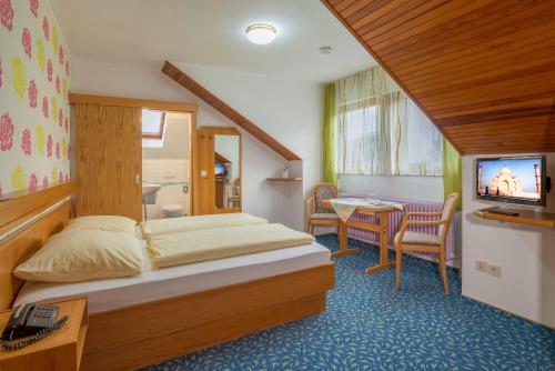 Schlafzimmer mit einem Bett, einem Tisch und einem TV in der Unterkunft Pension Kühns Mühle in Oestrich-Winkel