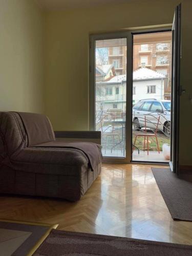 a living room with a couch and a sliding glass door at Apartmani Mićić in Vrnjačka Banja