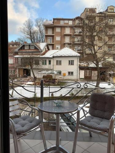 a table and chairs on a balcony with a view of a city at Apartmani Mićić in Vrnjačka Banja